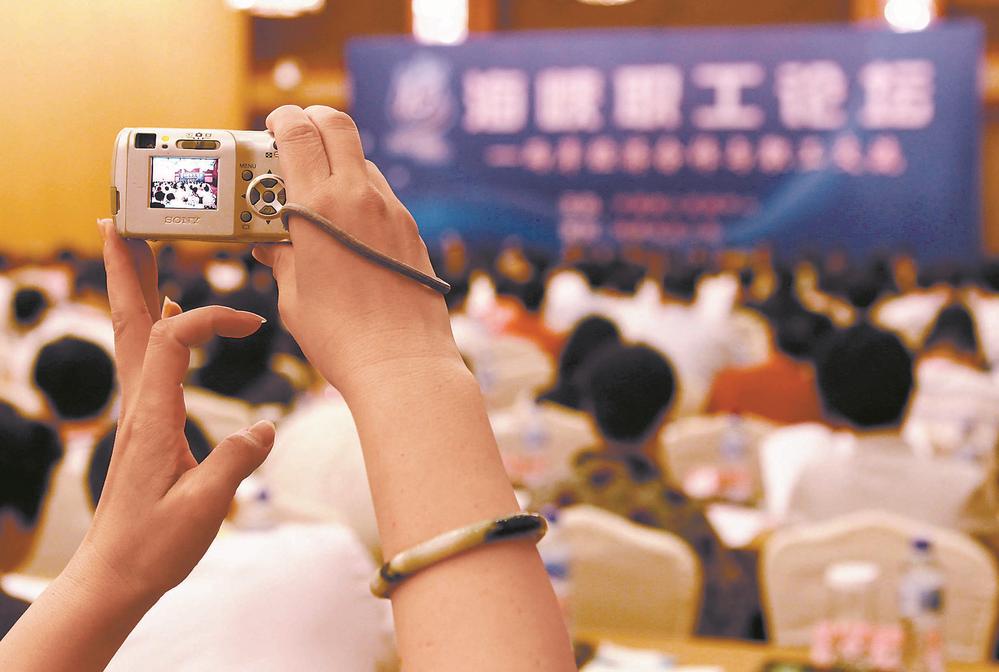 A representative of Taiwan Province who attended the meeting held up the camera in his hand to record the scene of the Straits Workers' Forum. (data picture)